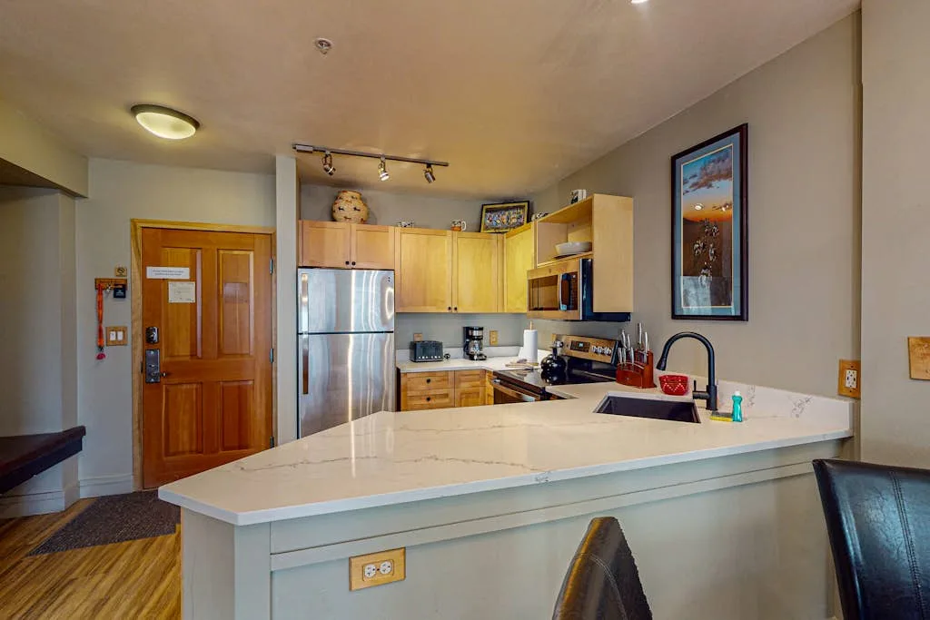 A kitchen with wooden cabinets, stainless steel appliances, and a wide island.