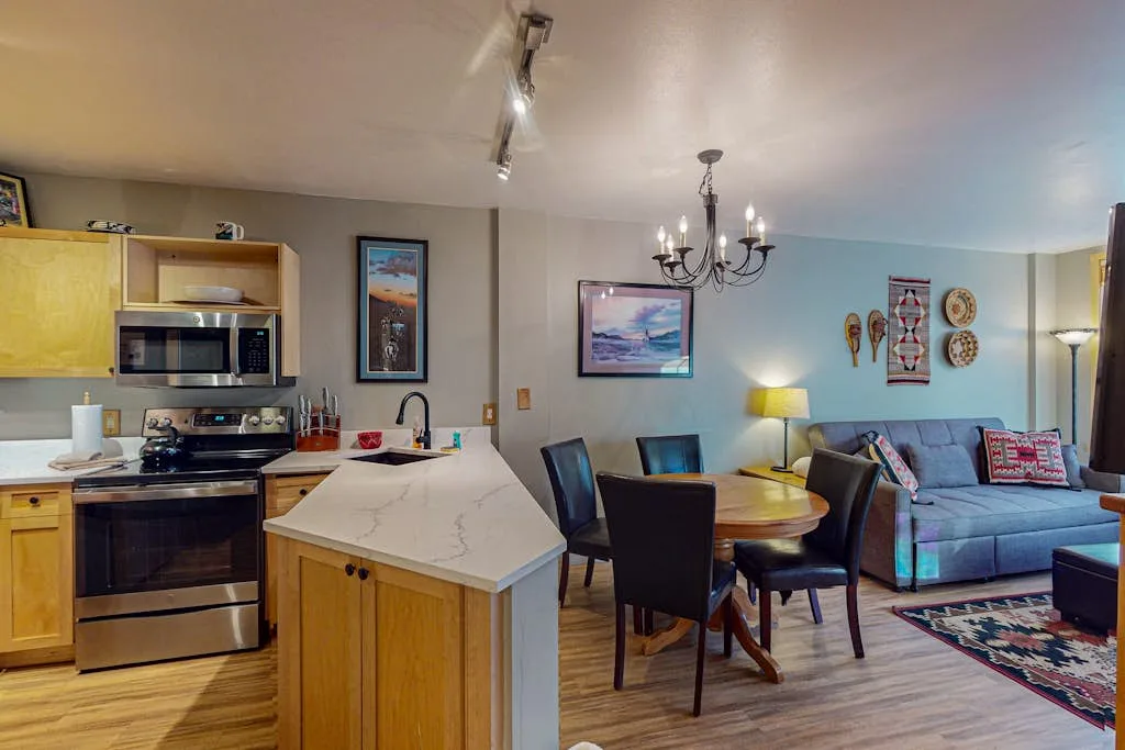 An open-plan kitchen and dining area connects to a living space with a sofa.