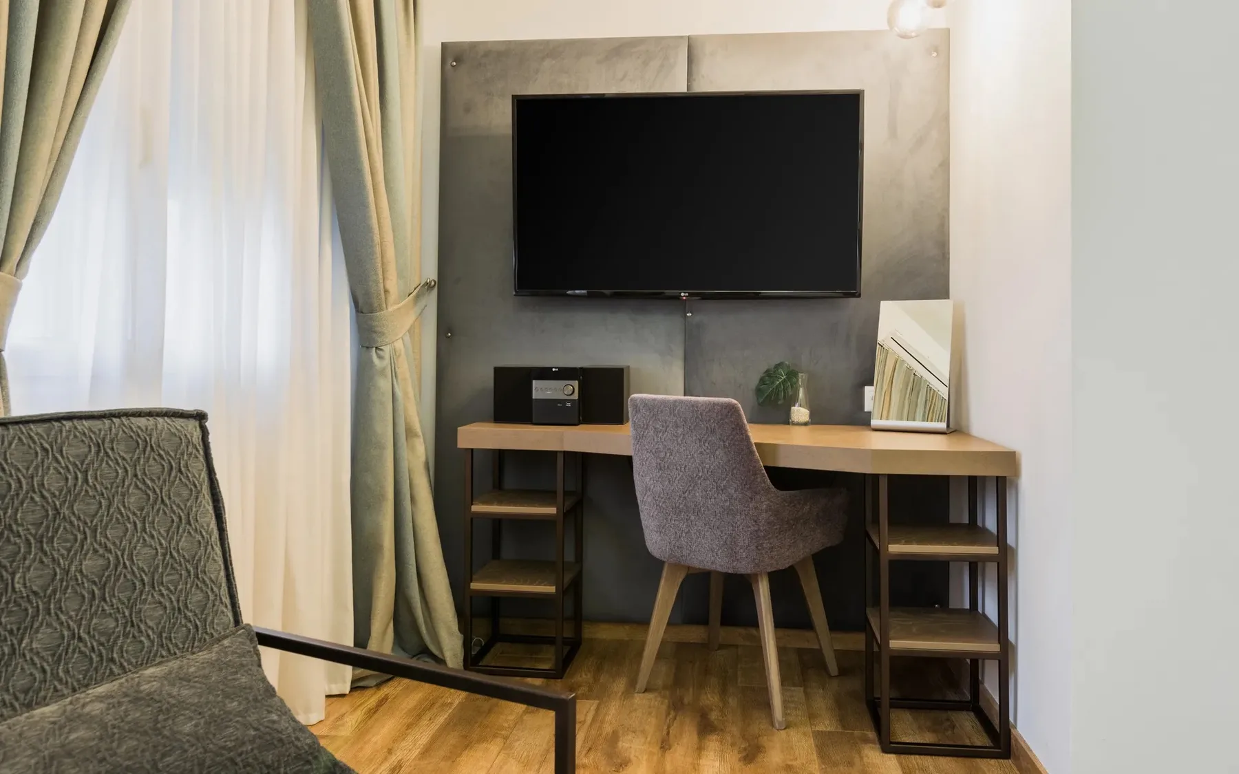 A bedroom workspace with a desk, chair, and wall-mounted television.