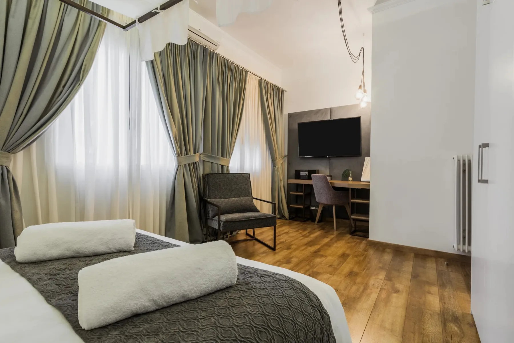 A bedroom with a bed, a chair, and a television.