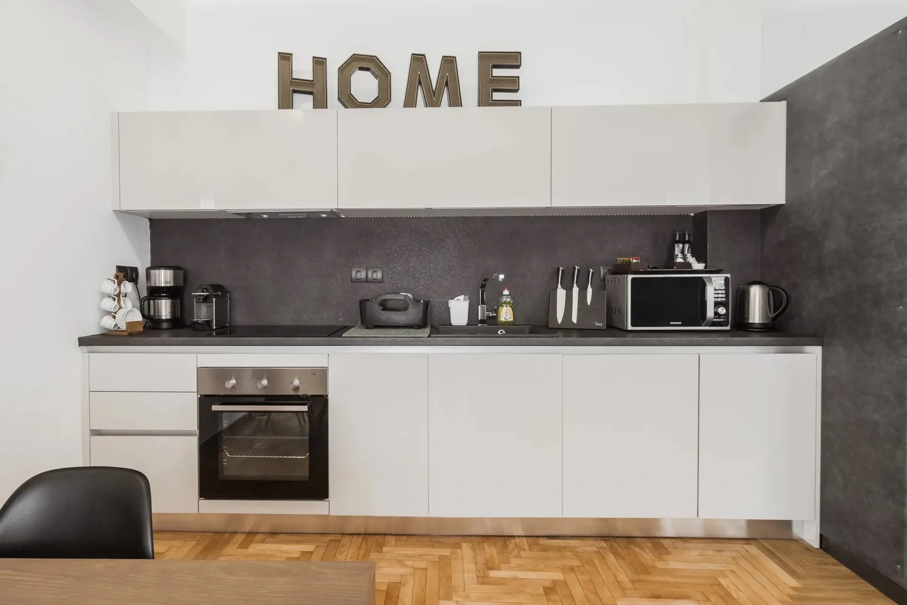 A modern kitchen with white cabinets, a countertop, and cooking appliances.