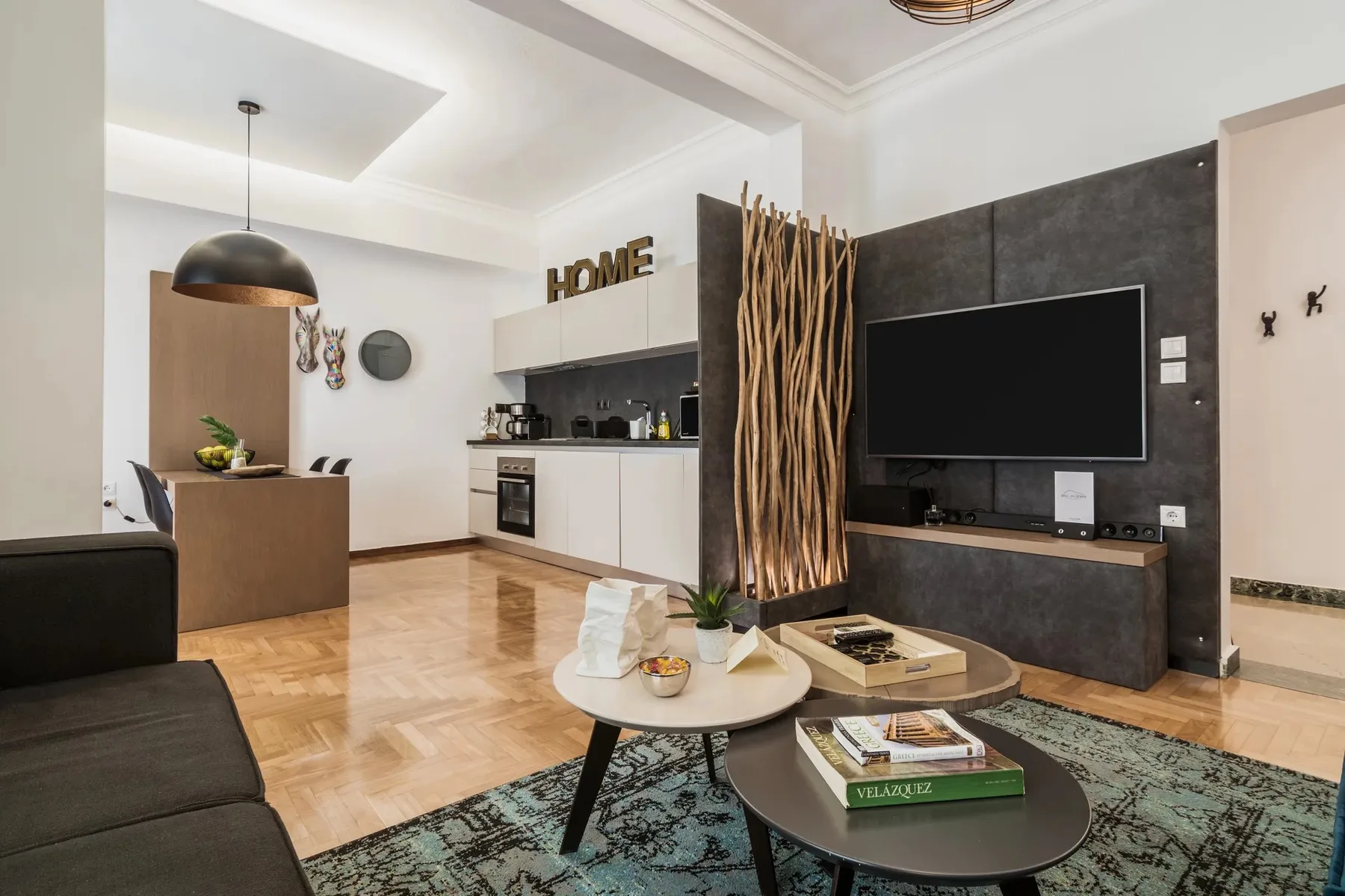 A modern living room with a television, seating, and an adjoining kitchen.