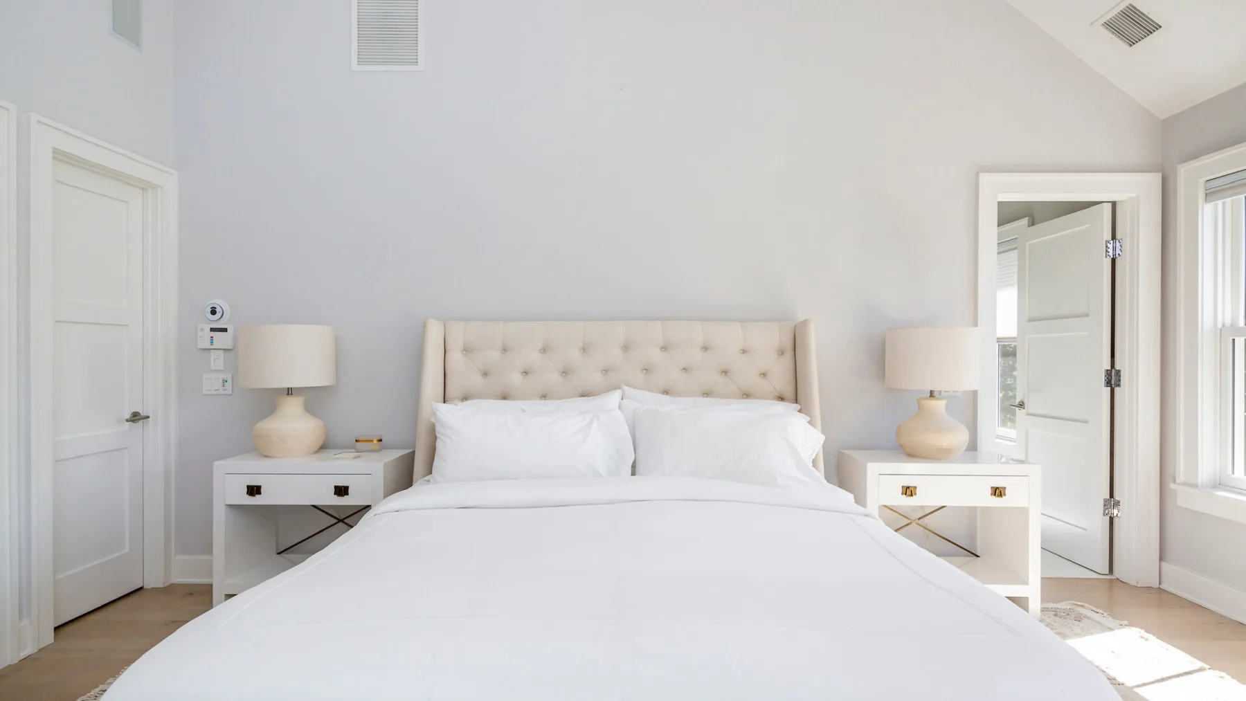 A bright bedroom with a neatly made bed and matching bedside tables.