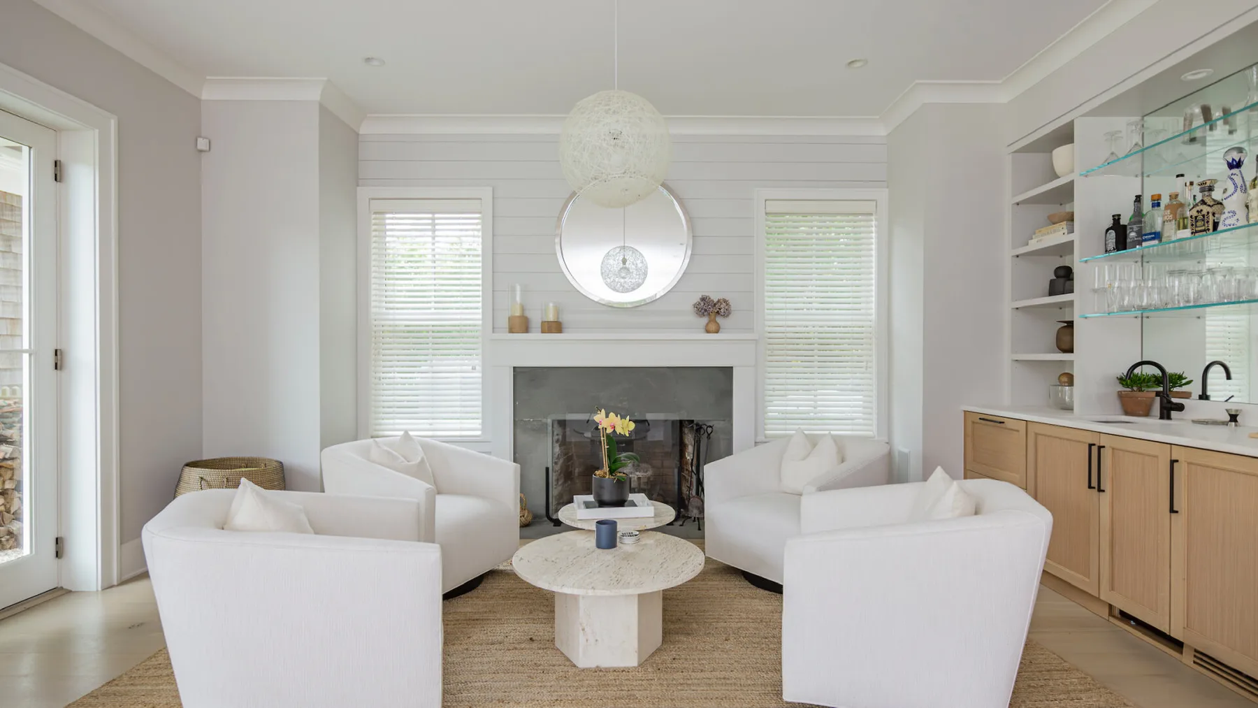A bright living room with white seating arranged around a round coffee table.