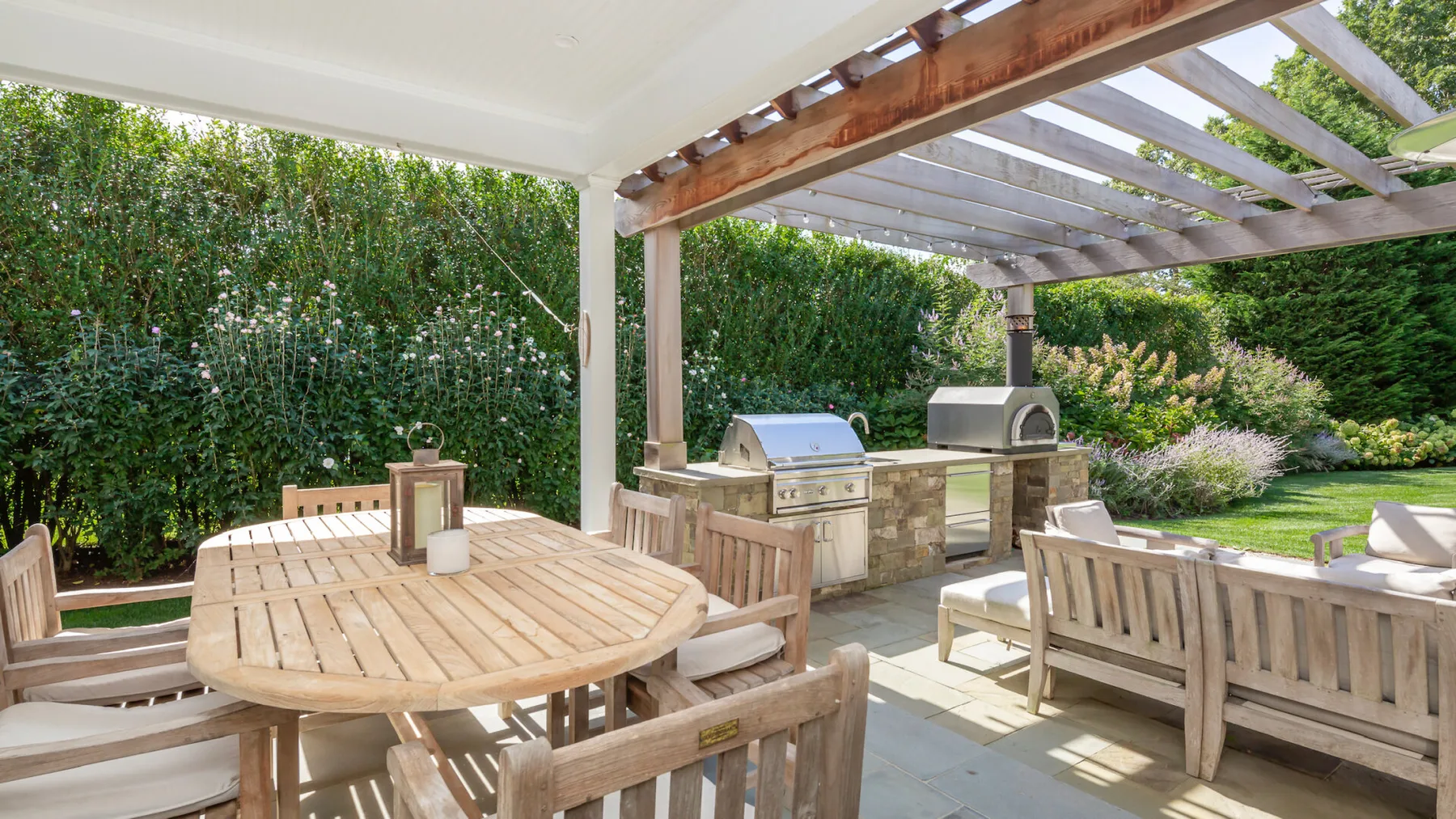 An outdoor patio dining area with wooden seating beneath a pergola.