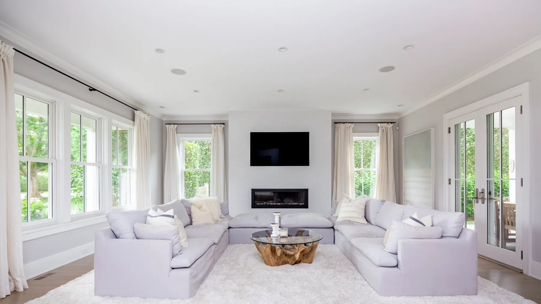 A bright living room with pale seating arranged around a low coffee table.