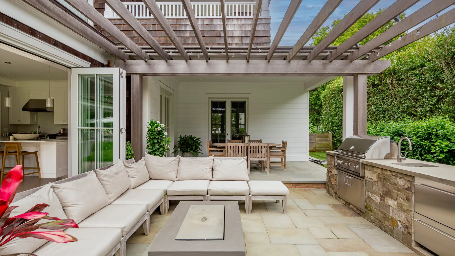 A covered outdoor patio with seating, a dining table, and an outdoor kitchen.
