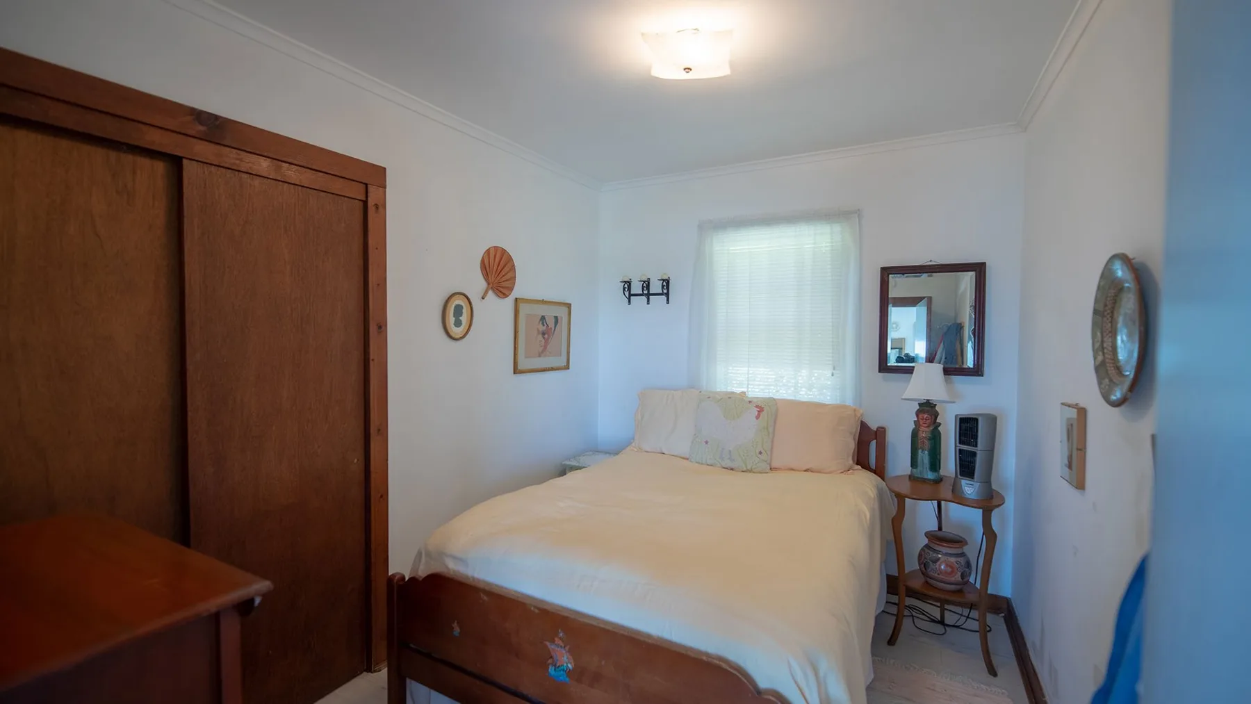 Un dormitorio con una cama, una mesita de noche y cuadros en la pared.