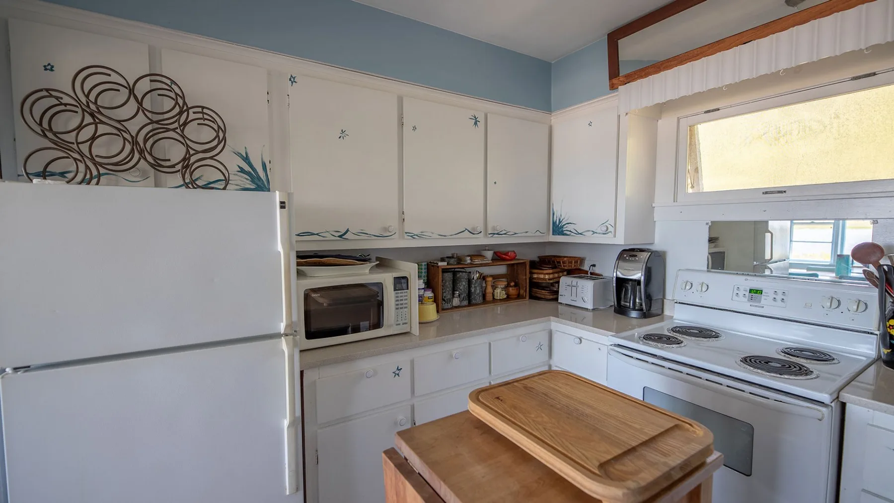 Una cocina con gabinetes blancos, un refrigerador y una estufa.