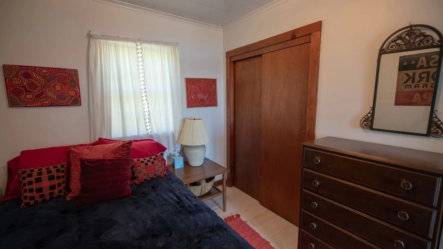 Un dormitorio con una cama, una puerta de madera y una cómoda.