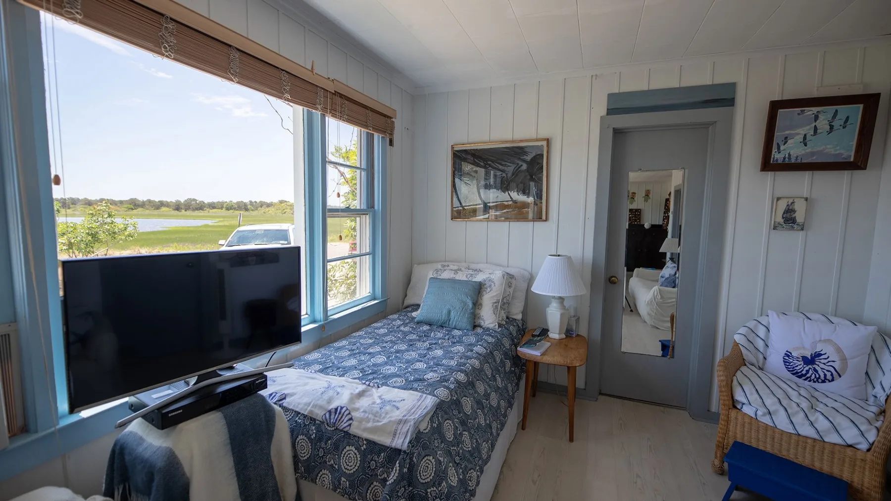 Un dormitorio con una cama, un televisor y una ventana con vistas a un paisaje verde.