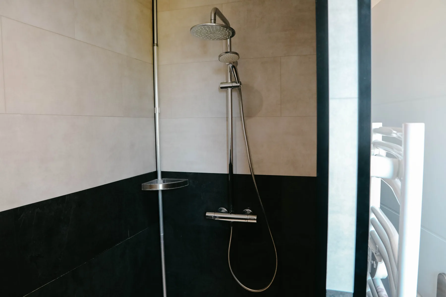 A tiled bathroom with a wall-mounted shower.