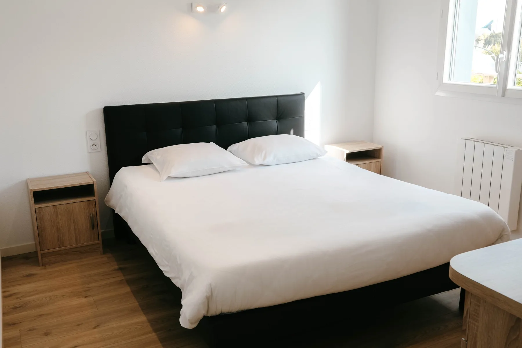 A bedroom with a bed and wooden bedside tables.