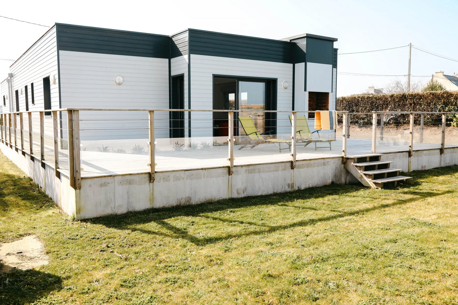 A modern home with a raised deck and outdoor seating.