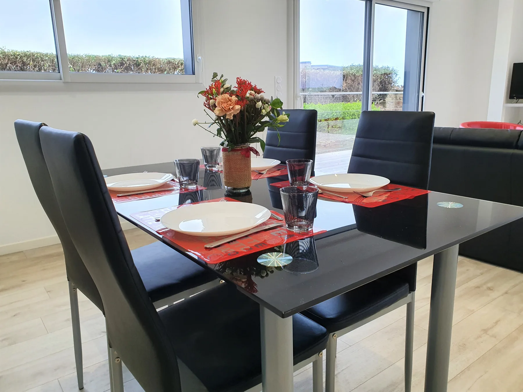 A dining area with a set table and large windows.