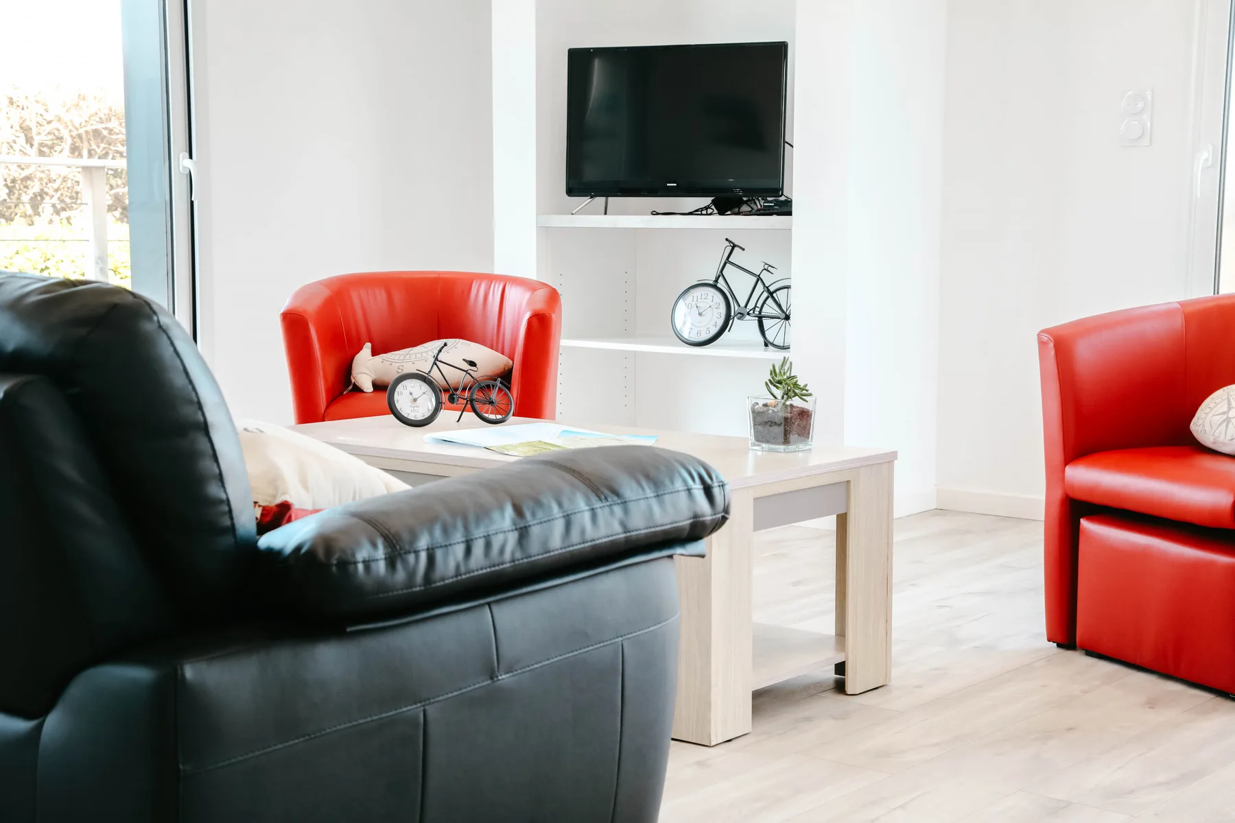 A bright living room with red seating and a television.