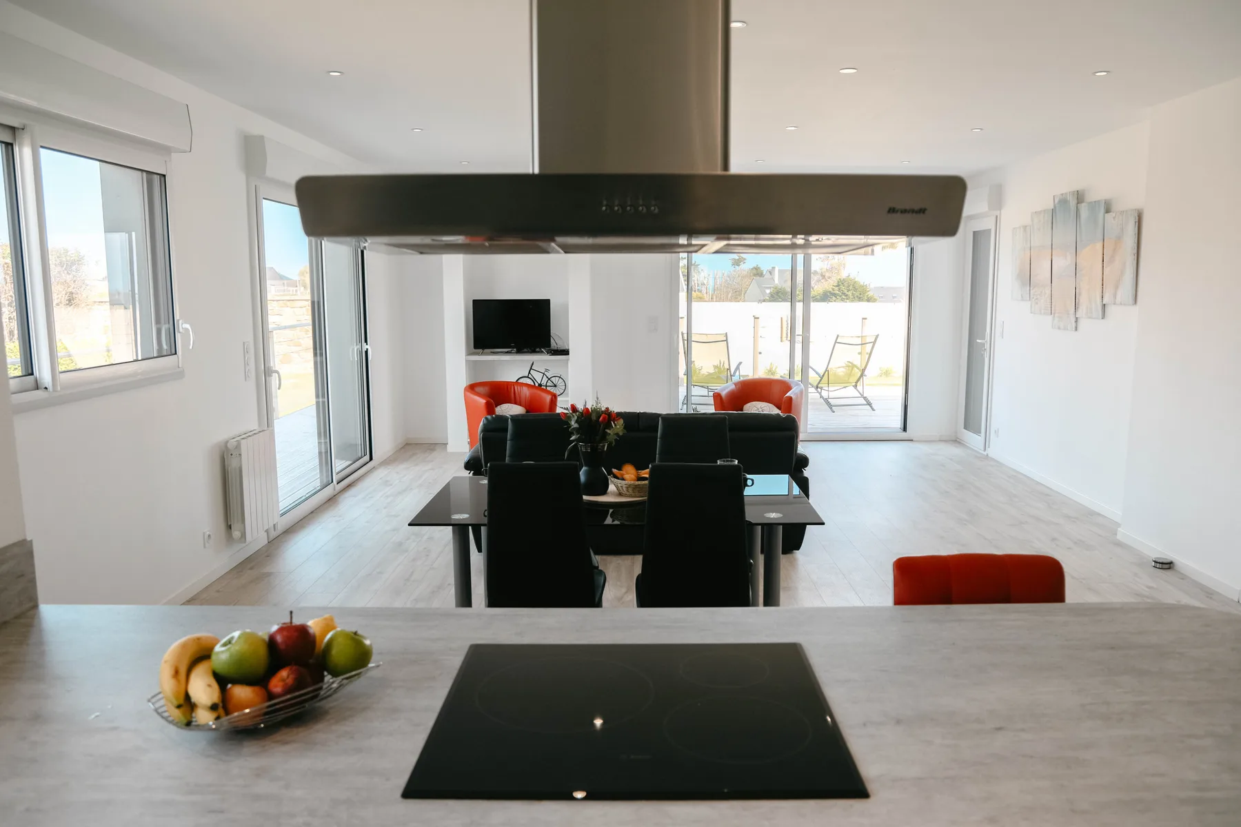 Open-plan dining and living area with a table, seating, and large windows.