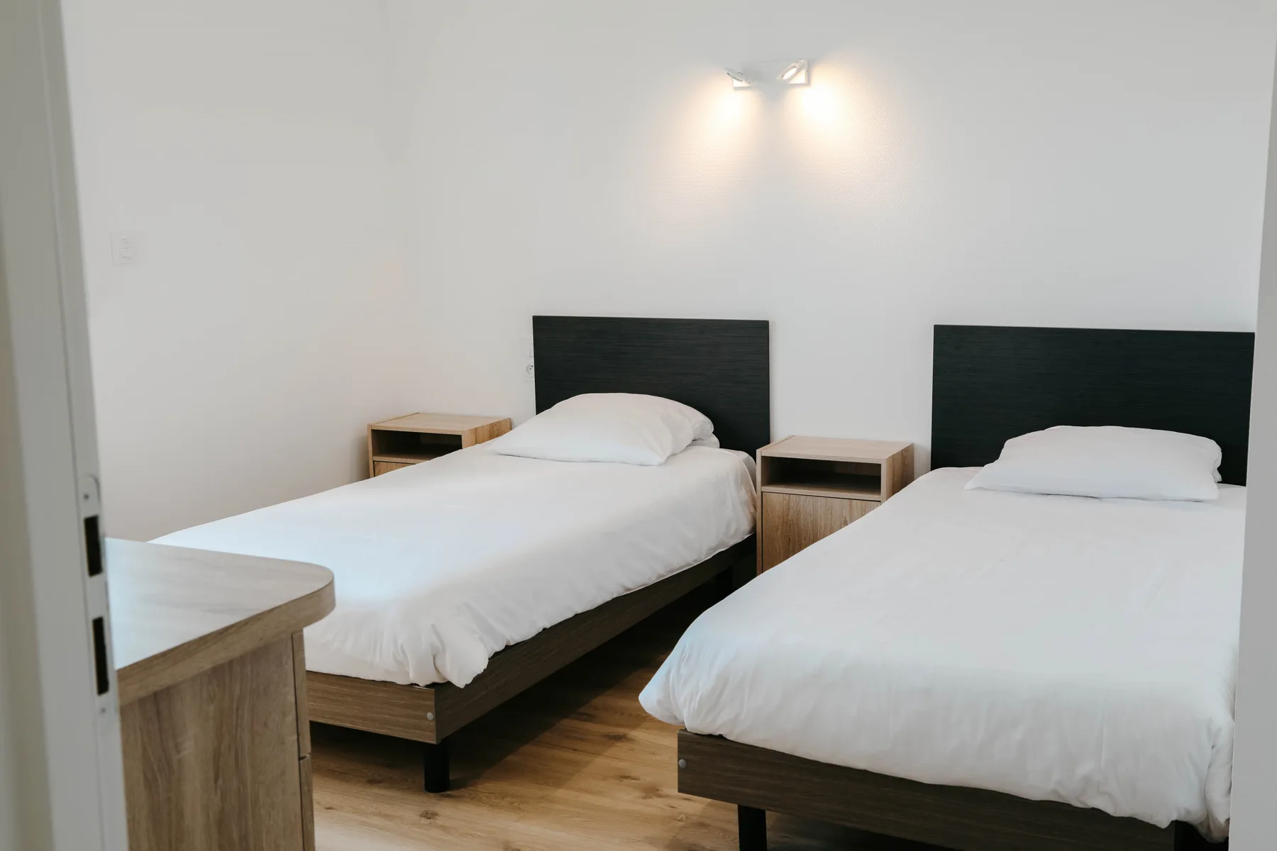 A bedroom with two single beds and a small bedside table.