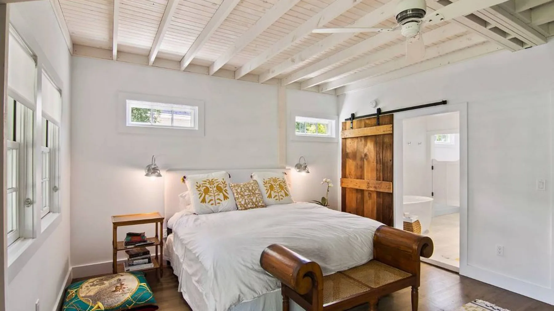 A bright bedroom with a bed, bedside tables, and a wooden sliding door.
