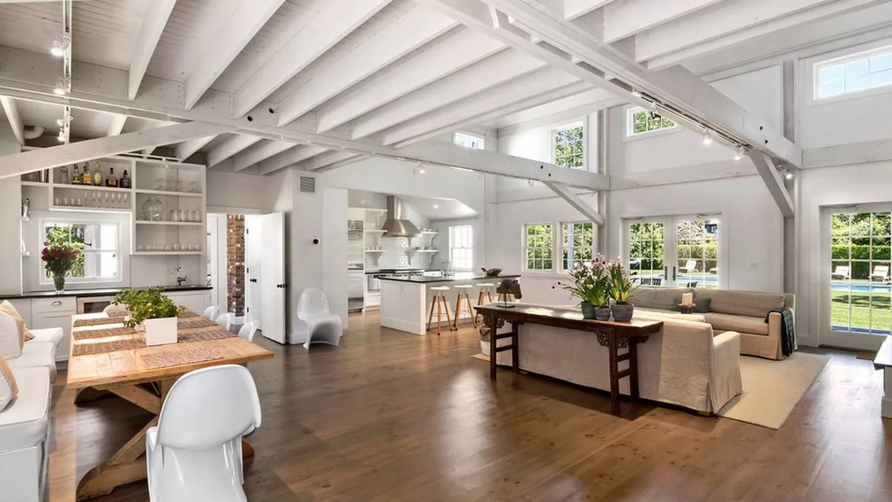 A bright open-plan living and dining area with large windows and exposed beams.