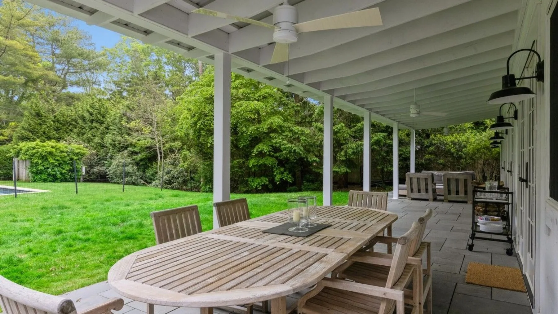 A covered outdoor dining area with a long wooden table and chairs.