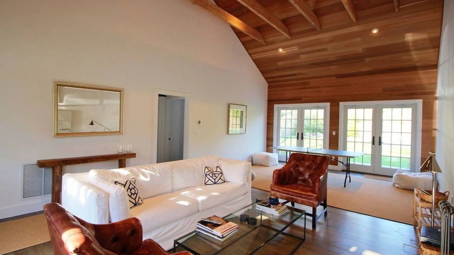 A bright living room with a white sofa and large windows opening onto a patio.