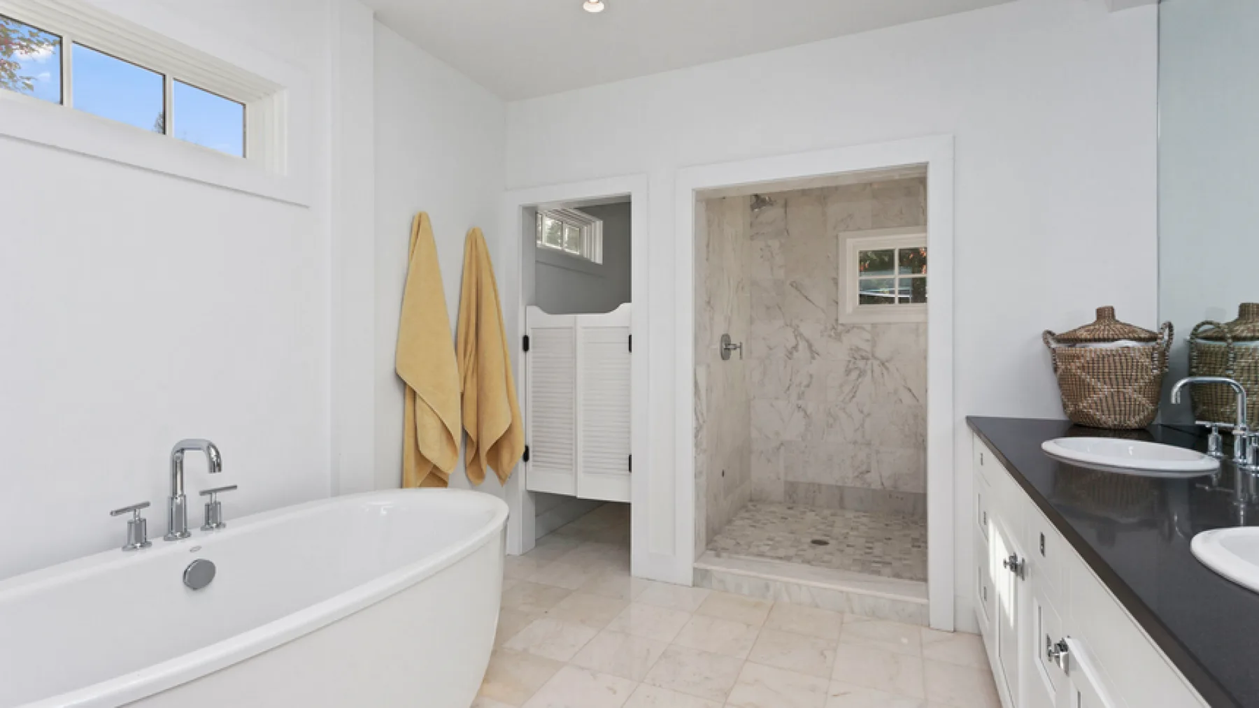 A bright bathroom with a bathtub, walk-in shower, and towels hanging on the wall.