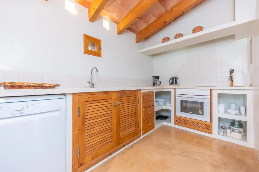A bright kitchen with wooden cabinetry, a countertop, and exposed ceiling beams.