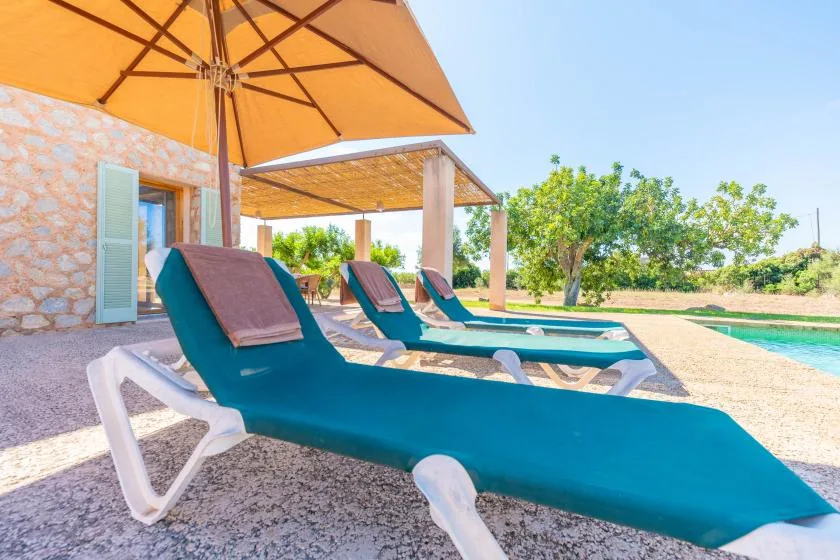 Outdoor lounge area with teal sun loungers beneath a large umbrella.