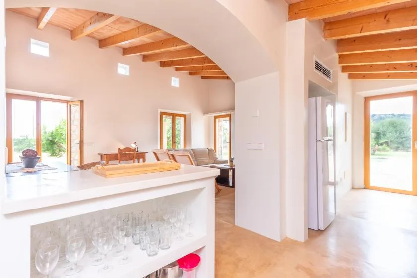 A bright open-plan living area with exposed wooden ceiling beams and large windows.