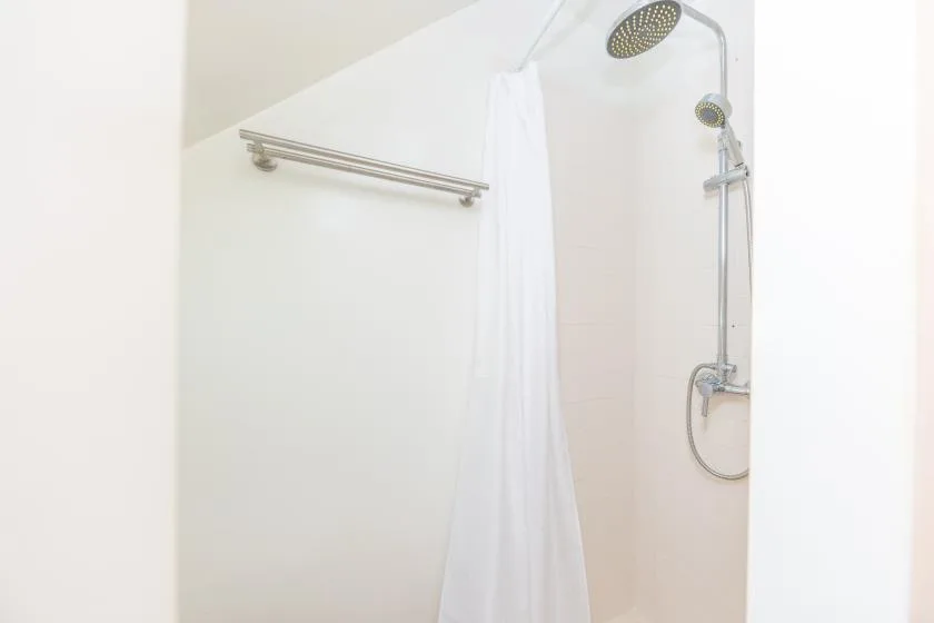A bright shower area with a handheld showerhead and curtain.