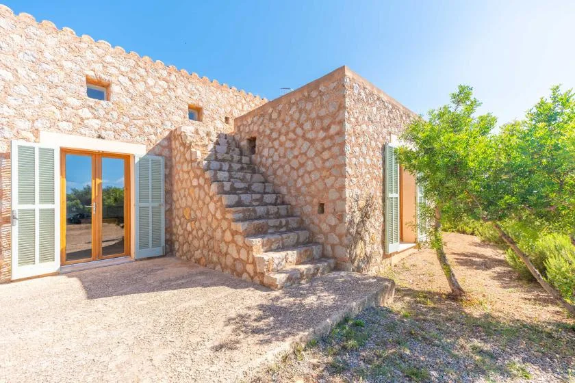 A stone building exterior with an outdoor staircase and glass doors.