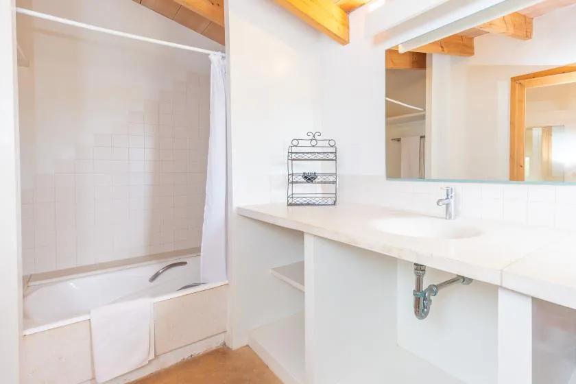 A bright bathroom with a bathtub, shower curtain, and long vanity.