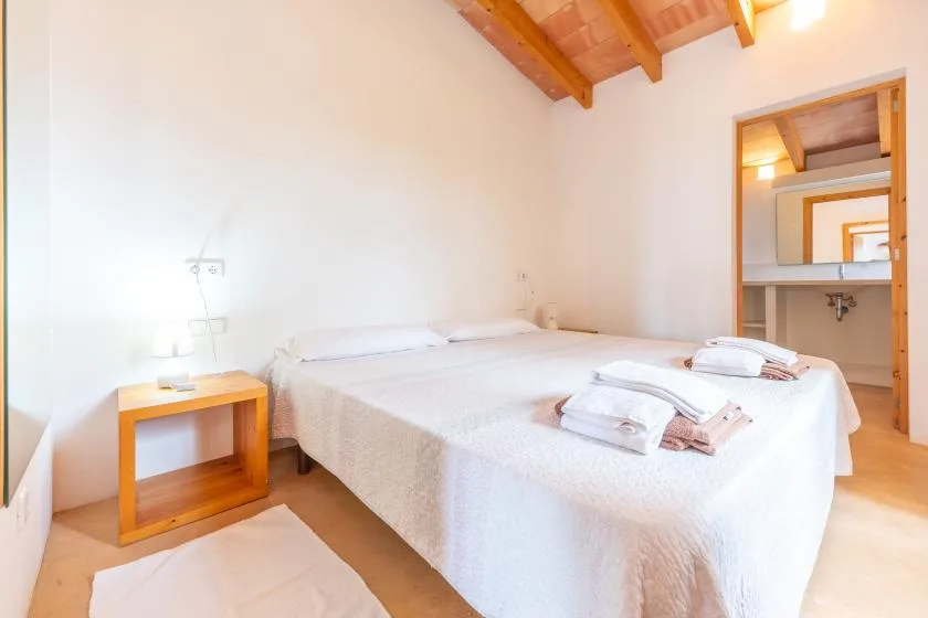 A bedroom with a double bed, bedside table, and an open doorway to a bathroom.