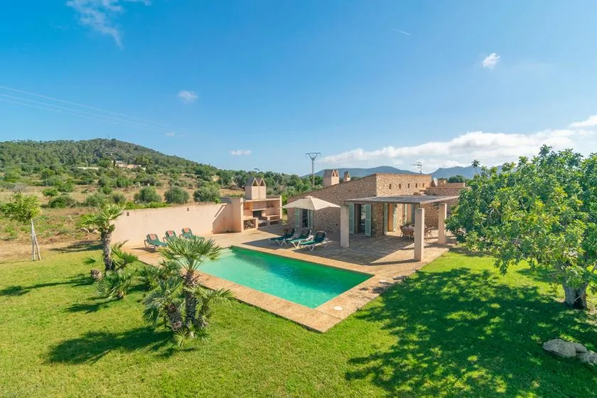 A modern house and swimming pool sit in a landscaped rural setting.