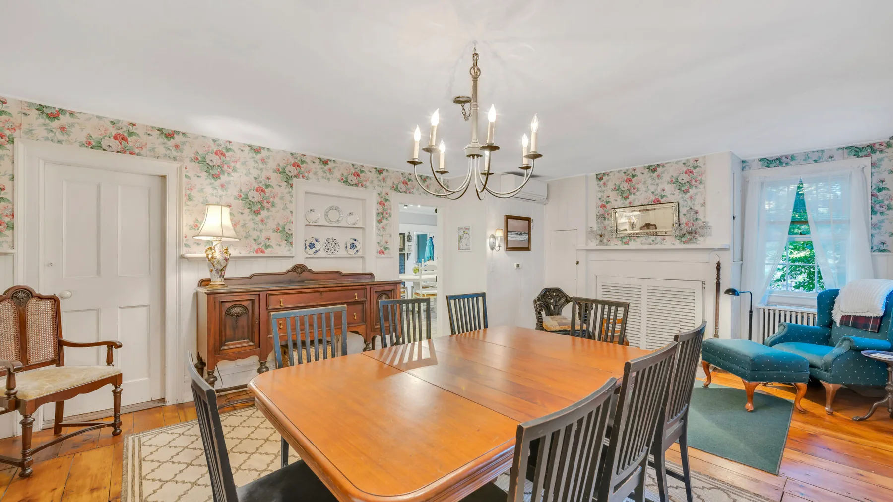 Un comedor con una gran mesa de madera y papel tapiz floral.