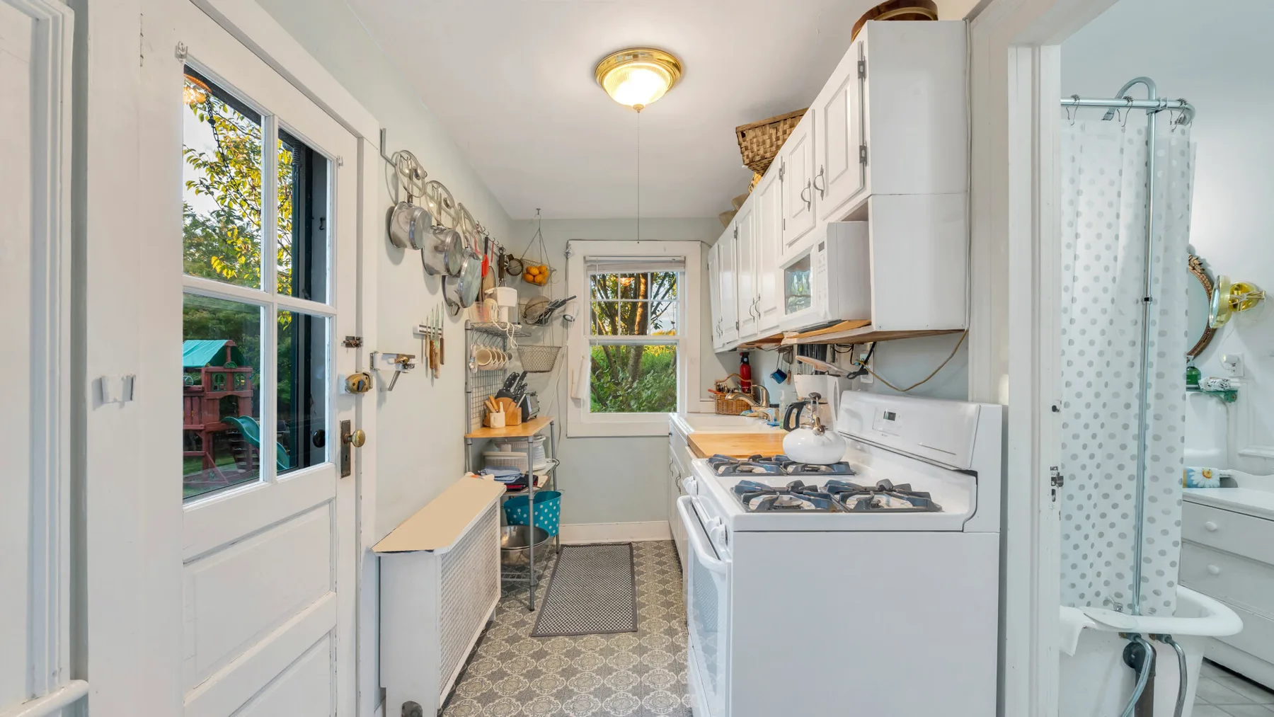 Una cocina estrecha con gabinetes blancos, una estufa y una ventana.