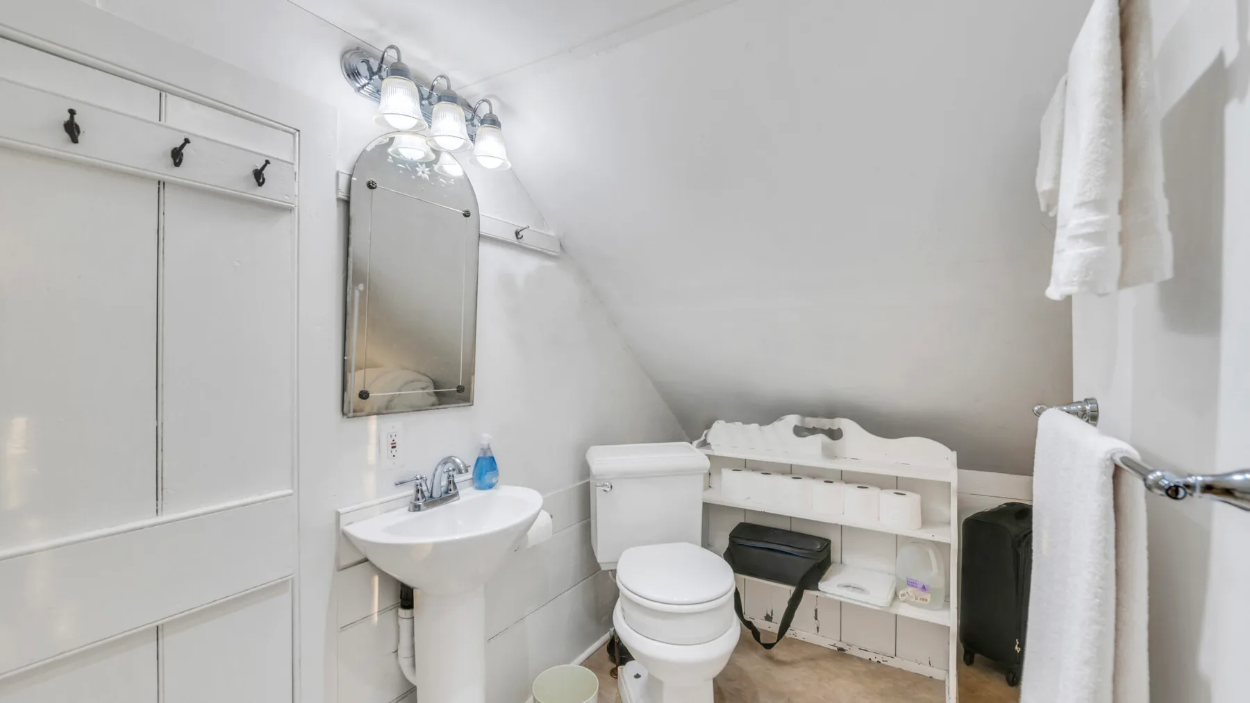 Un baño luminoso con lavabo, inodoro y estantería abierta.