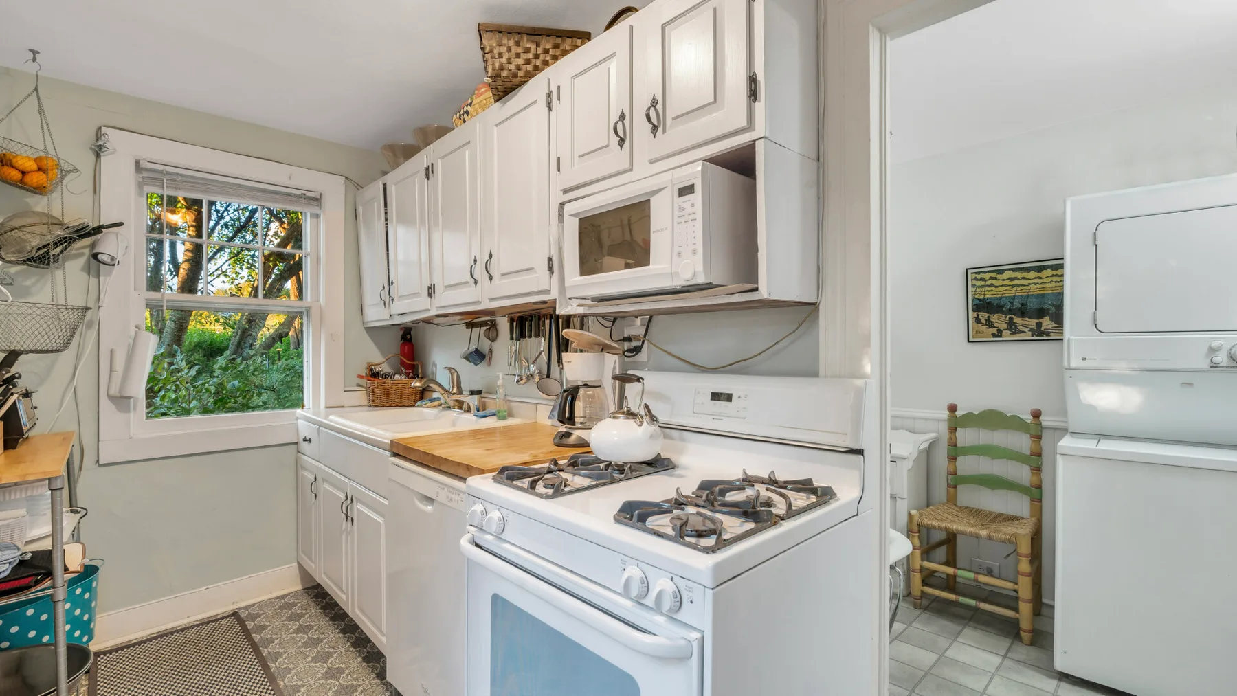 Una cocina luminosa con gabinetes blancos y una estufa de gas junto a una ventana.