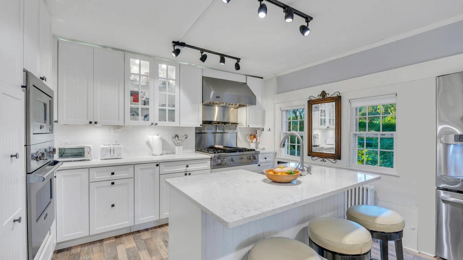 Una cocina luminosa con gabinetes blancos, una isla central y ventanas.