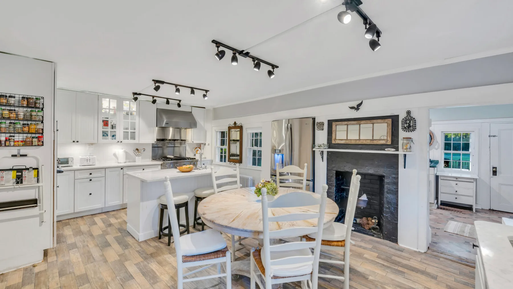 Una luminosa cocina y zona de comedor con armarios blancos y una mesa redonda.