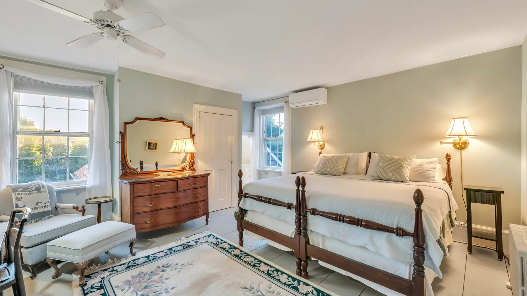 Un dormitorio con una cama grande, una cómoda de madera y ventanas.