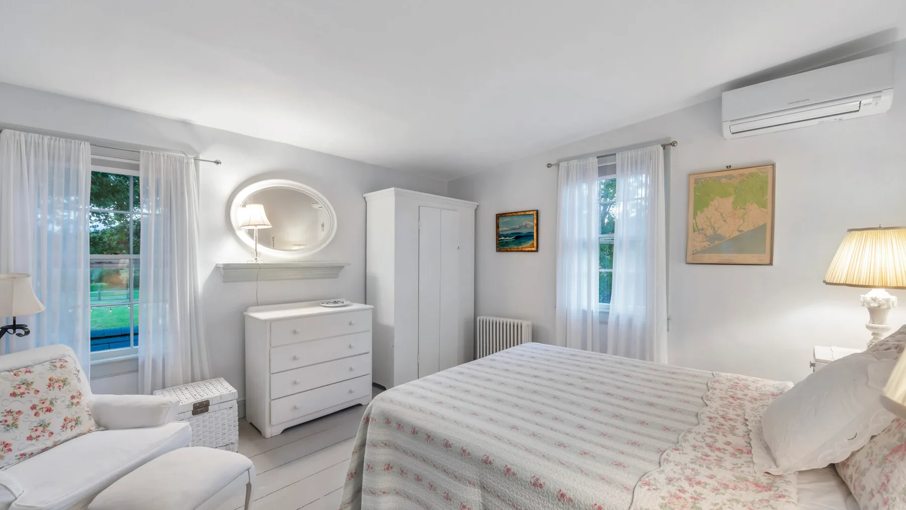 Un dormitorio luminoso con una cama, una cómoda y ventanas con cortinas.