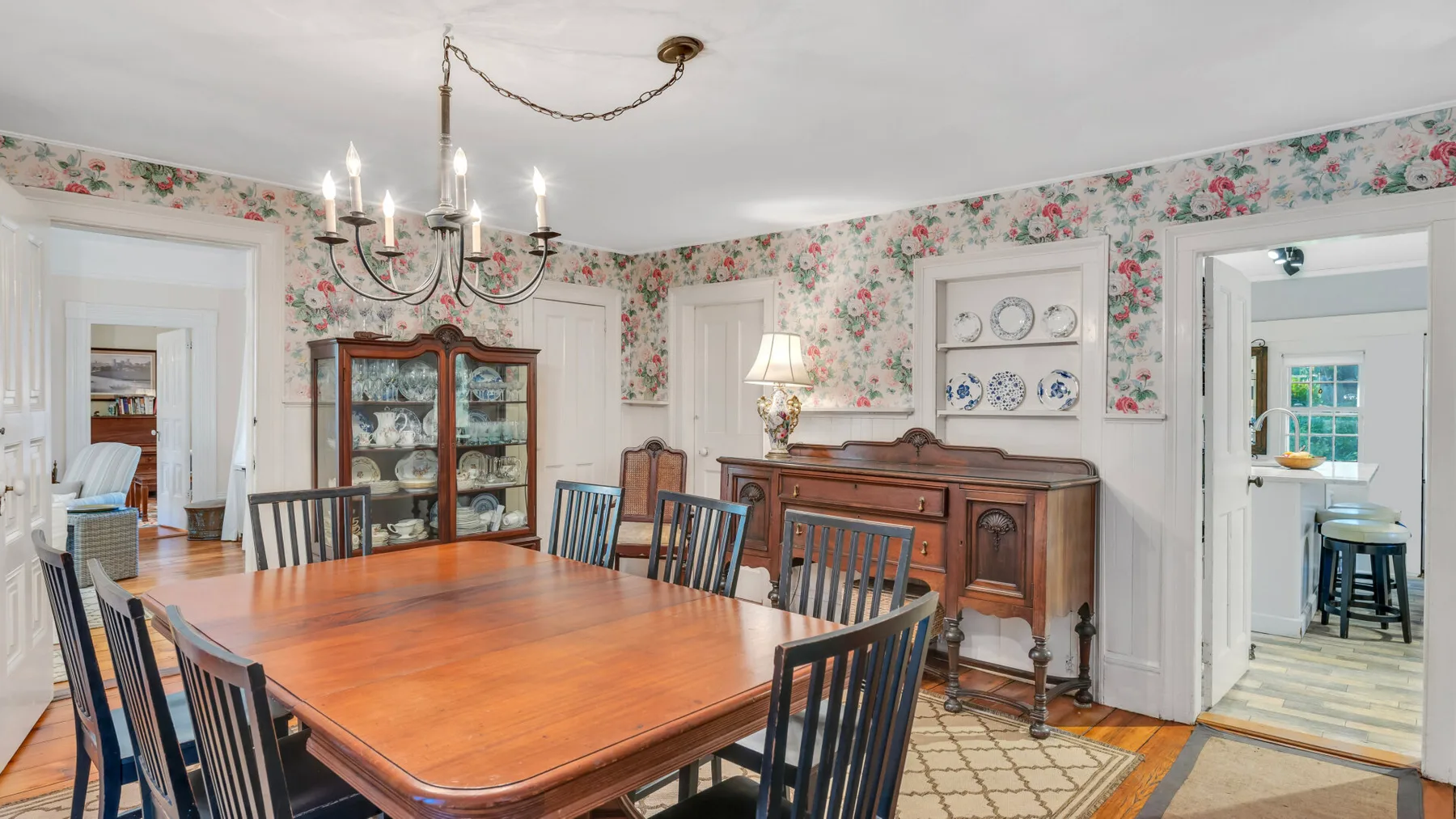 Comedor con una mesa grande de madera y papel tapiz floral.