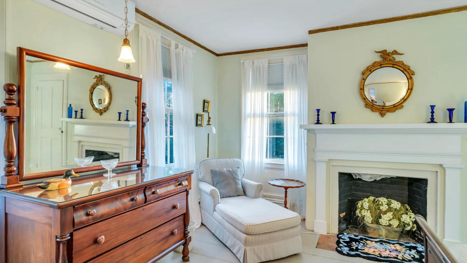Una sala de estar luminosa con chimenea, asiento tapizado y cómoda de madera.