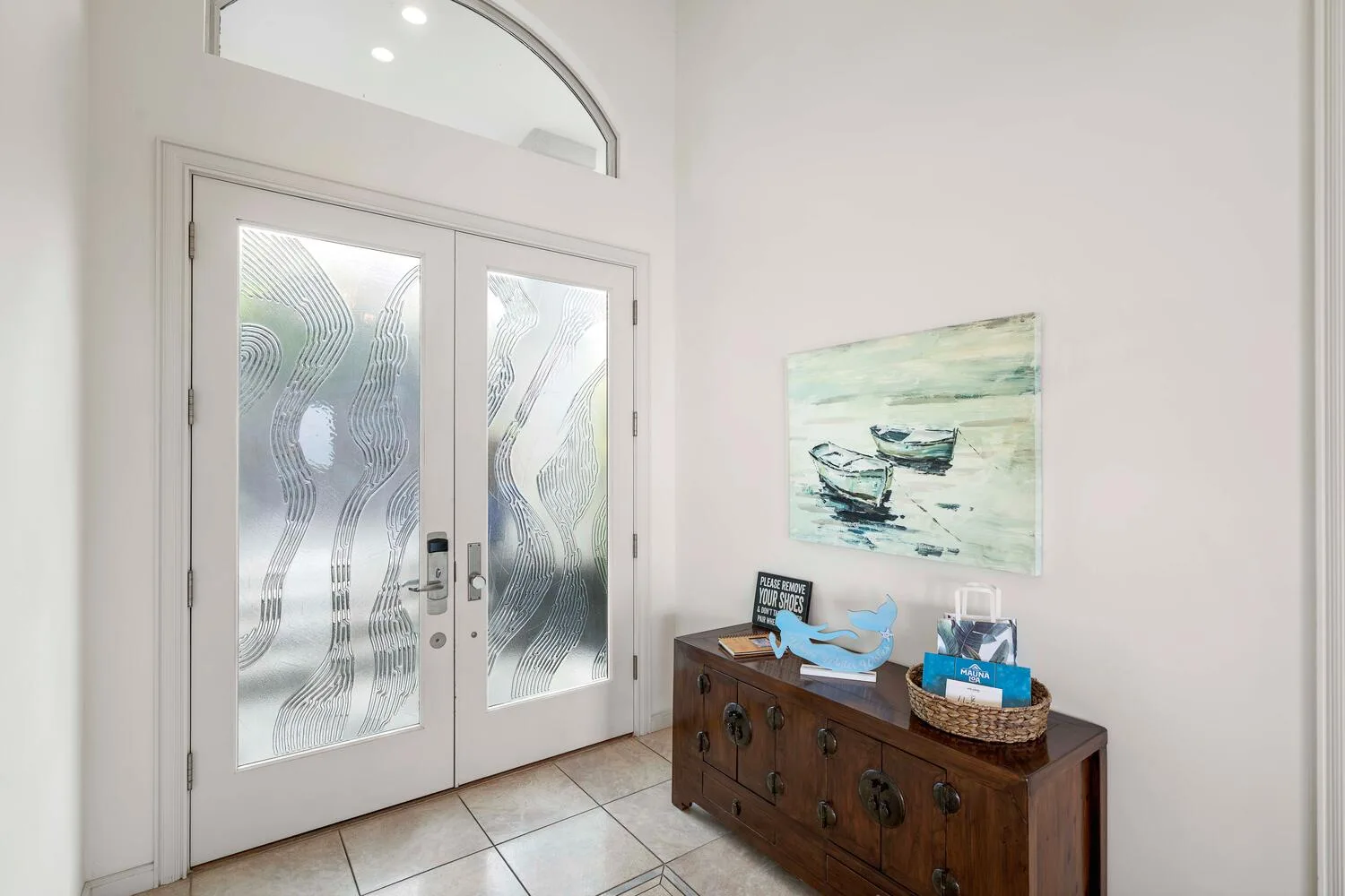 A bright entryway features patterned glass doors and a wooden console.