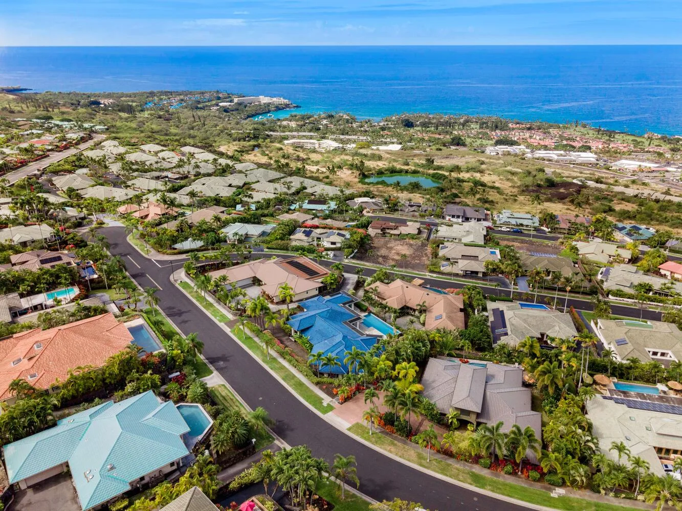 Aerial view of a coastal residential neighborhood with the ocean in the distance.