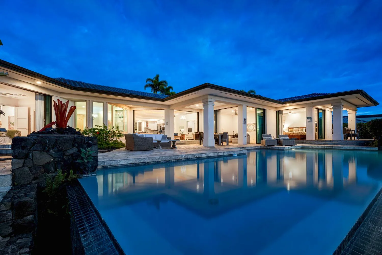 Modern house with a broad swimming pool illuminated at dusk.