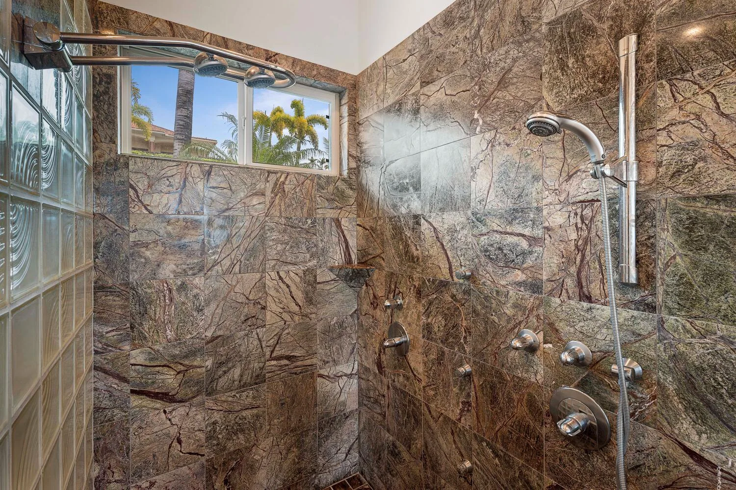 A tiled shower area with a handheld showerhead and a window.
