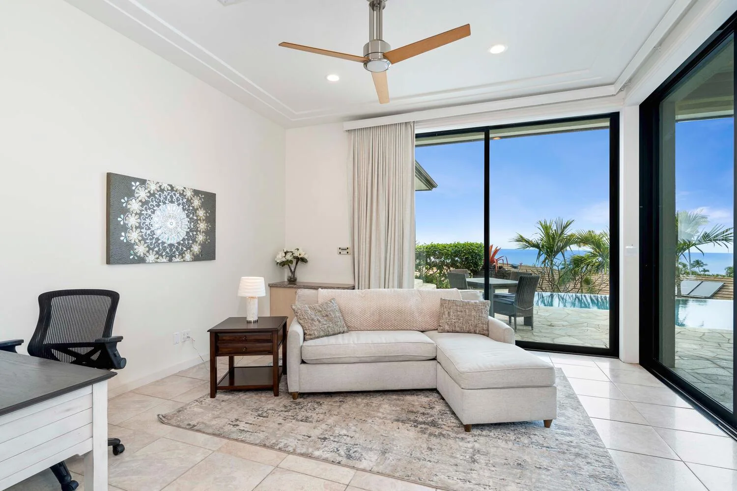 A bright living room with a sectional sofa and large glass doors overlooking a pool.